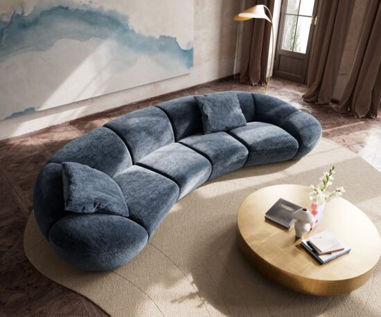 XXL Sofa mit organischer Form auf einem Teppich mit Couchtisch und großem Kunstwerk im Hintergrund