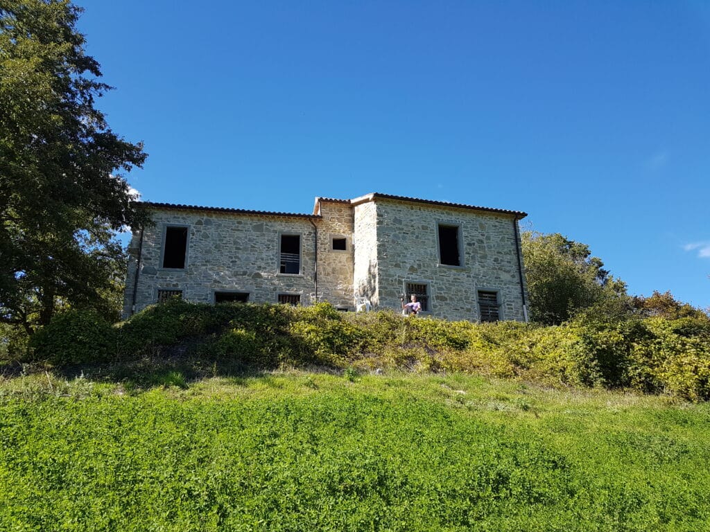 Blick auf ein Rustico / Steinhaus in Italien, das zum Verkauf steht mit einem großen Garten / Wiese im Vordergrund